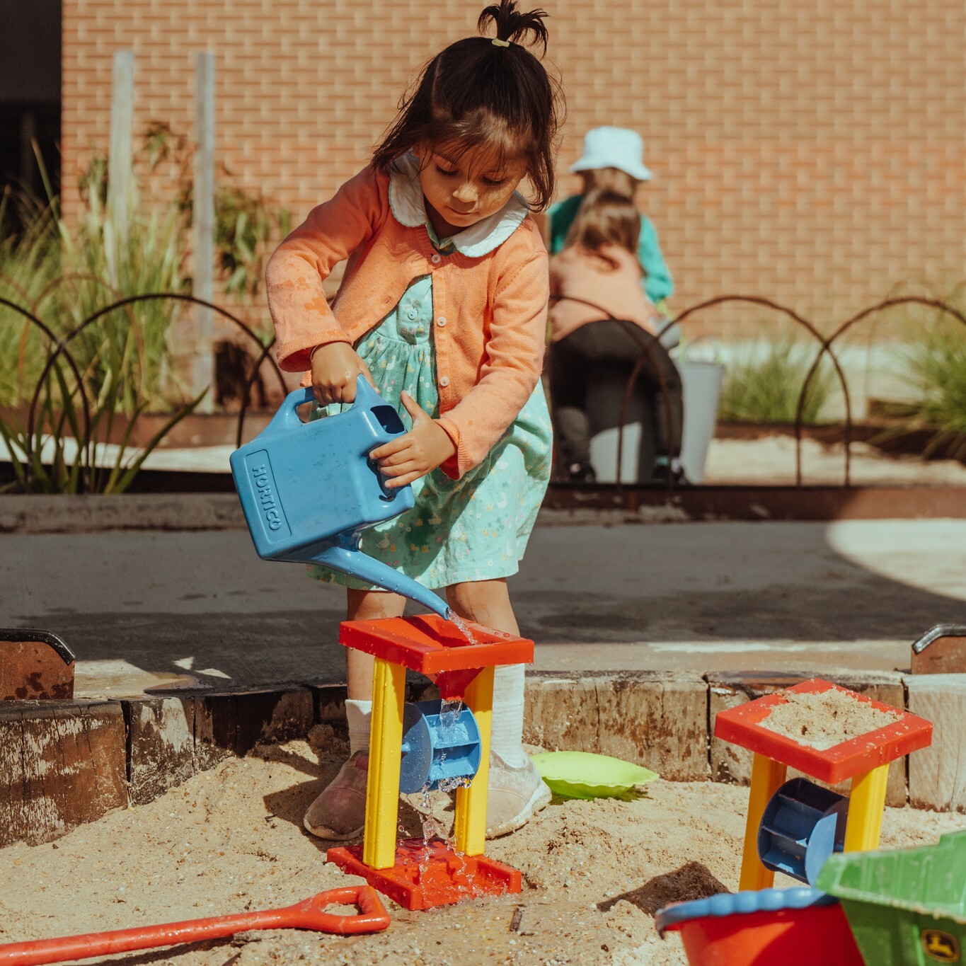 A child at a kindergarten plays with a watering can