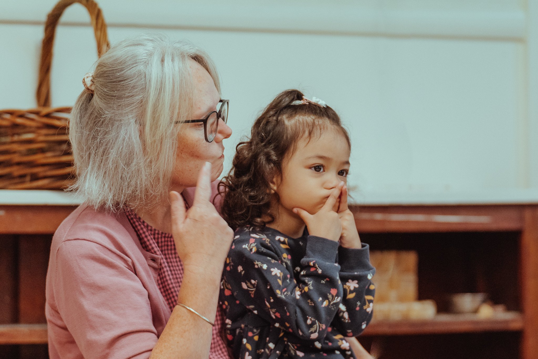 An educator and a child pointing to their faces